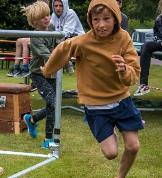 Een jongen die over het gras rent tijdens het vakantie zomerkamp freerunning